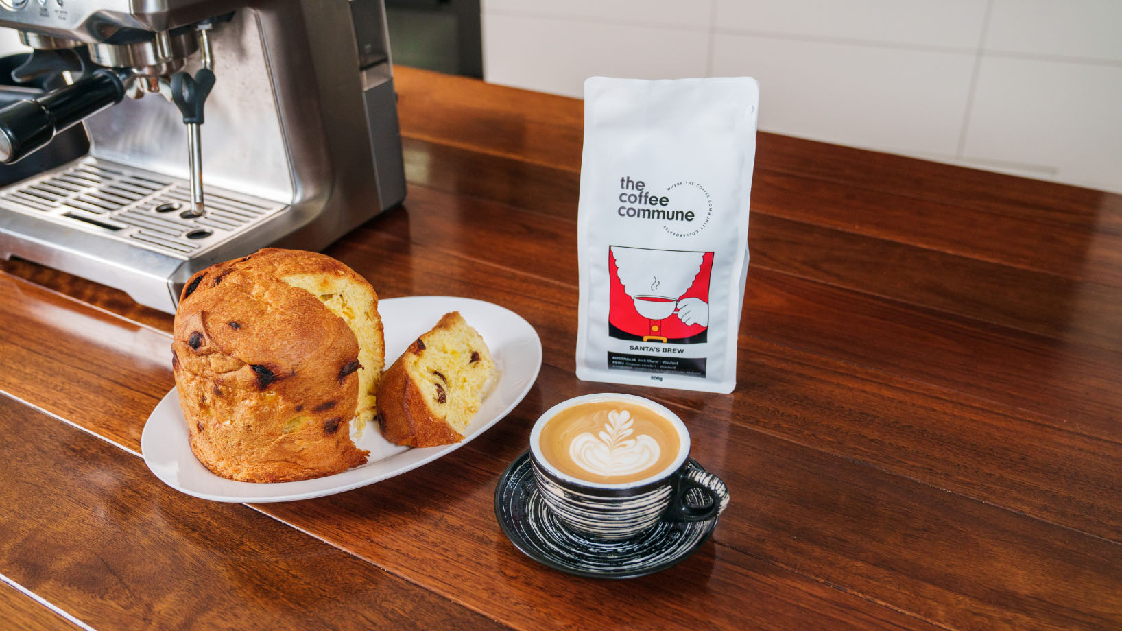 christmas coffee beans, flat white and panettone on a kitchen table with coffee machine in the background